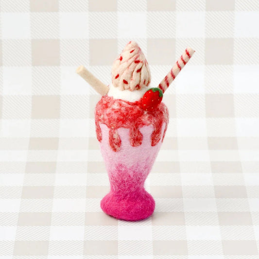 Pink and red milkshake with a cherry on top against a striped background