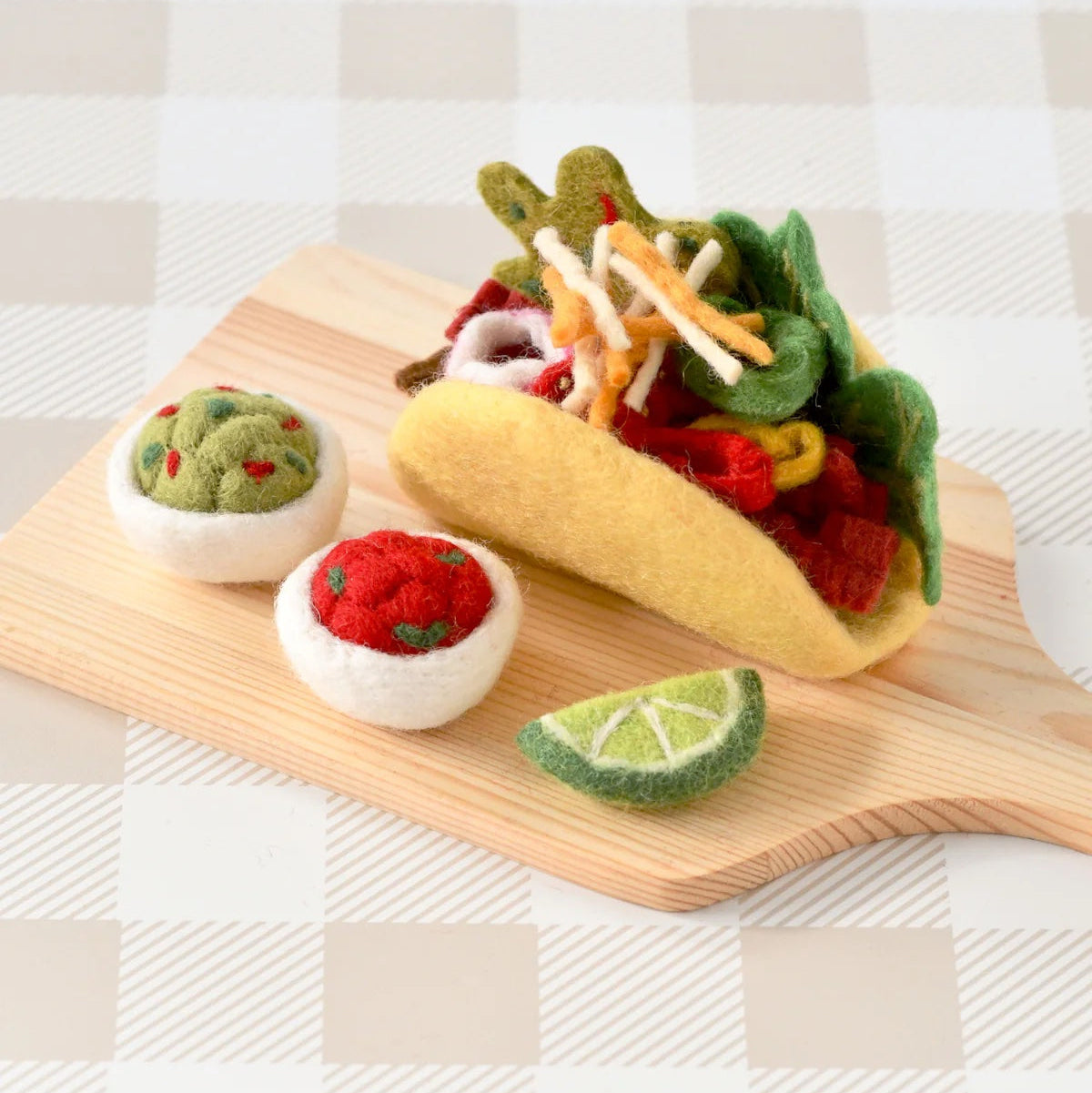 Felt food taco set on a wooden board with a checkered background