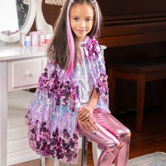 Young girl in a colorful outfit sitting on a stool in a room with a piano.