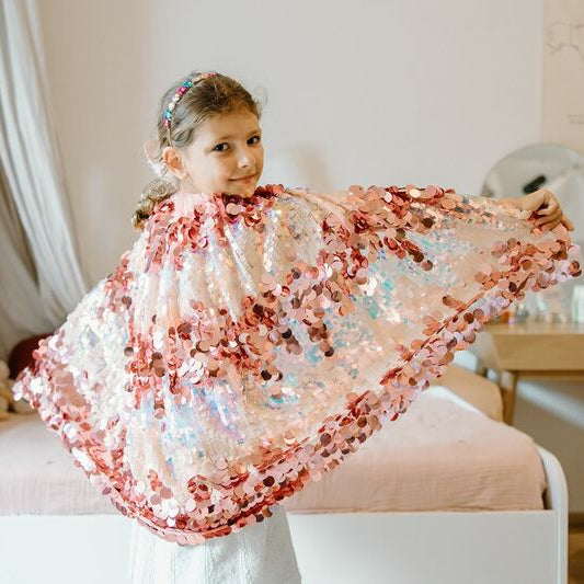 Young girl holding a floral shawl in a bedroom setting