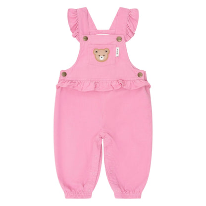 Pink baby romper with ruffled straps and teddy bear design on a light pink background