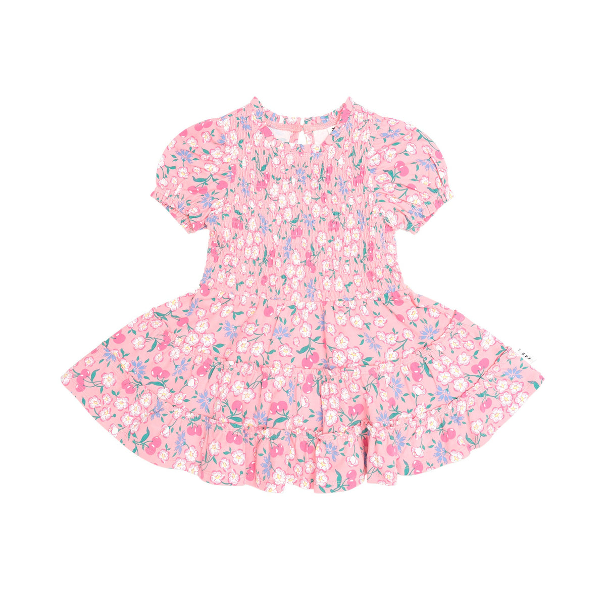 A pink short-sleeve dress with a dense floral and abstract print in pink, purple, and green, featuring a smocked bodice and ruffled hem, shown flat on a white background.