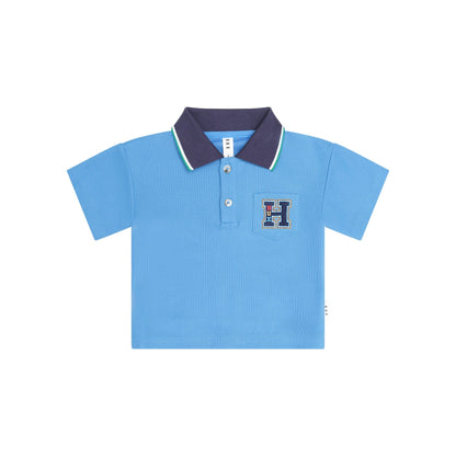 A light blue short-sleeve polo shirt for kids, featuring a dark navy blue collar with thin green and white stripes, a two-button placket, and a decorative embroidered letter 'H' patch on the left chest.