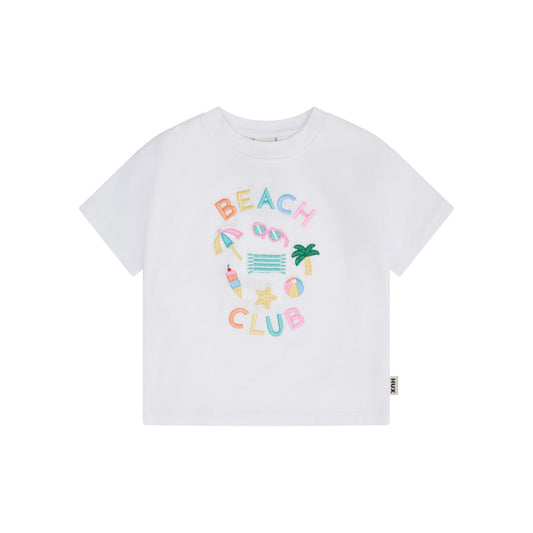 A white short-sleeve crewneck t-shirt featuring a colorful 'BEACH CLUB' graphic on the front with beach-themed illustrations, shown against a plain white background.
