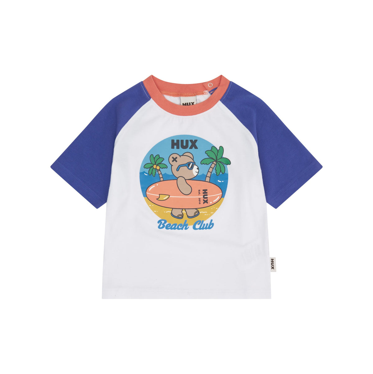 A children's short-sleeve raglan t-shirt by HUX, featuring a white body, royal blue sleeves, and a coral orange collar. The front is decorated with a colorful cartoon graphic of a bear on a beach with the text 'HUX Beach Club'.