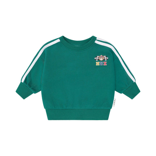 Green sweatshirt with white stripes on sleeves and colorful logo on a beige background