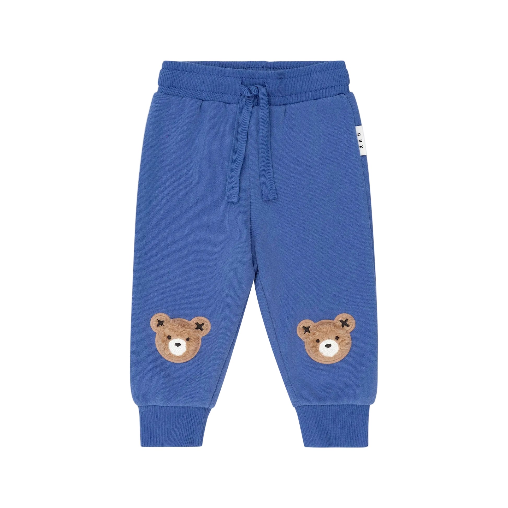 Blue children's sweatpants with bear face patches on a beige background