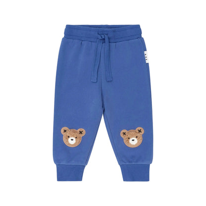 Blue children's sweatpants with bear face patches on a beige background