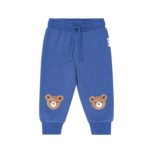 Blue children's sweatpants with bear face patches on a beige background