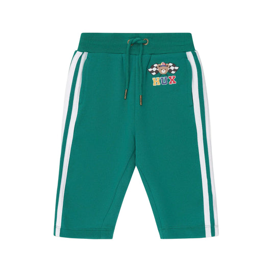 Green jogger pants with white stripes on a beige background