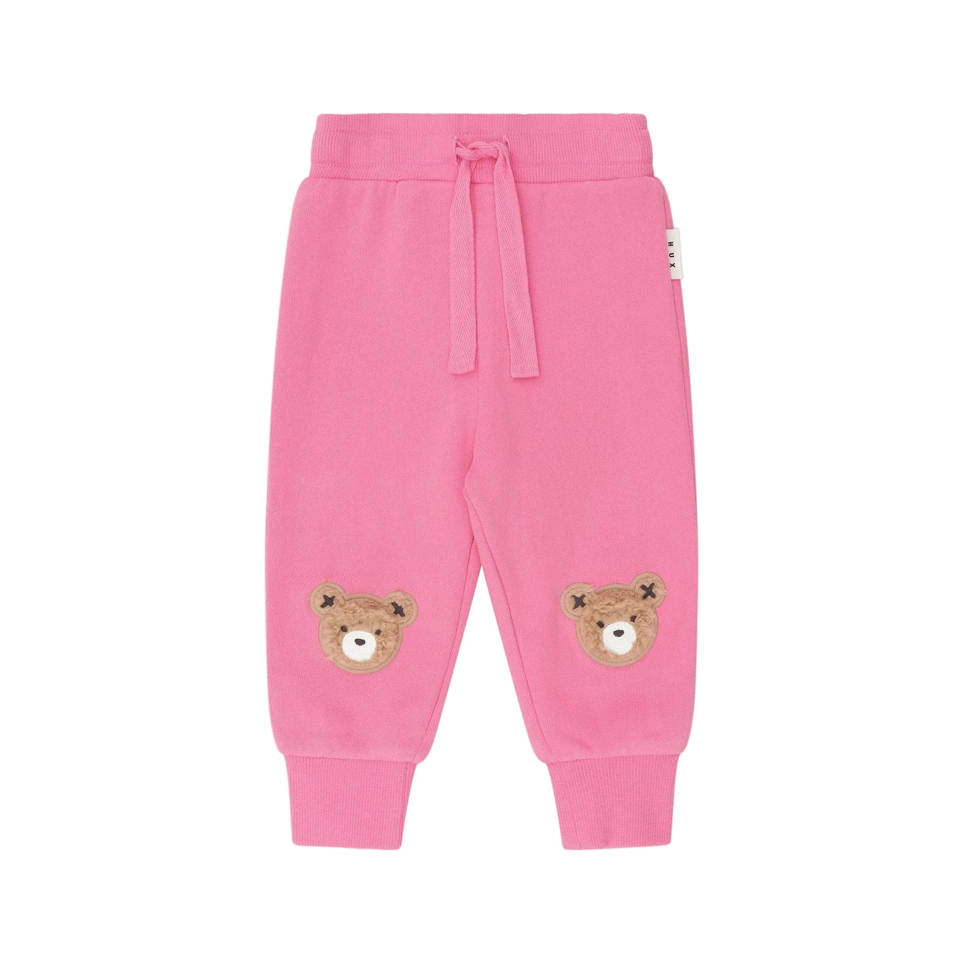 Pink children's sweatpants with bear patches on a white background