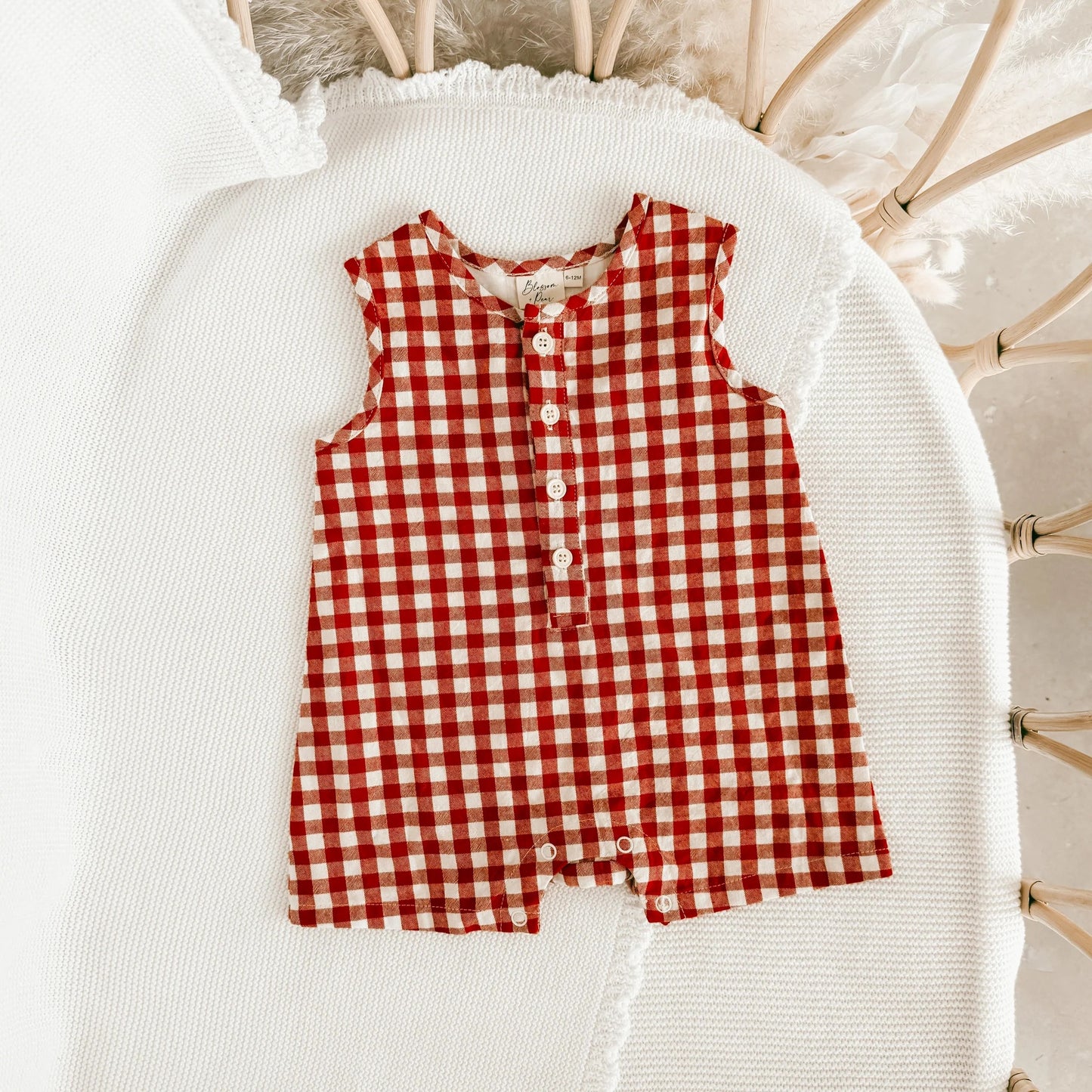 Red and white checkered romper on a white surface with a neutral background