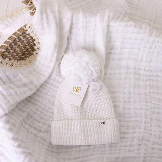 White knit beanie with a logo on a textured white surface