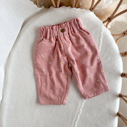 Pink children's pants with floral pattern on a textured surface