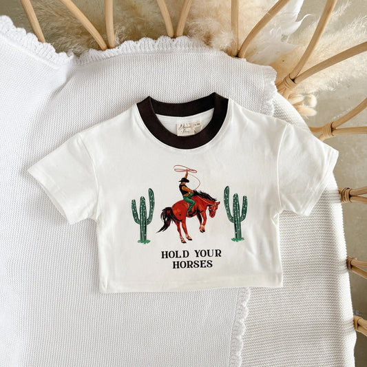 White t-shirt with cowboy and cactus design on a textured surface