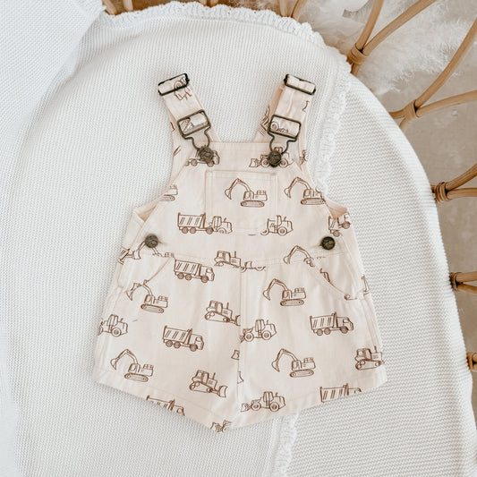 Baby overalls with construction vehicle pattern on a white surface