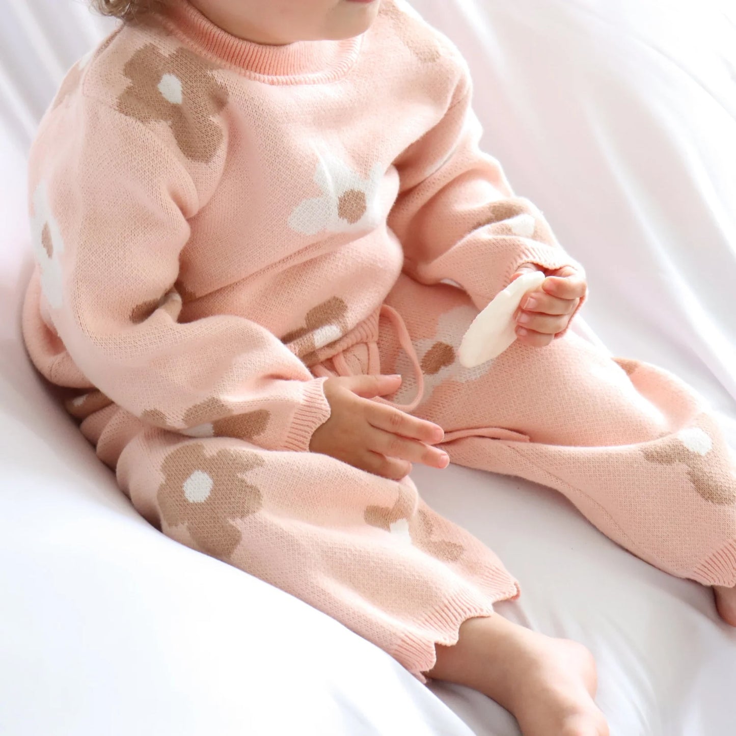 Child wearing a pink outfit with bear designs on a white background