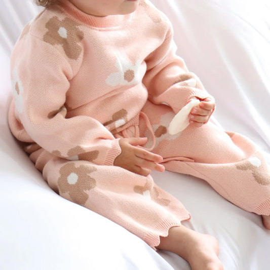 Child wearing a pink outfit with bear designs on a white background