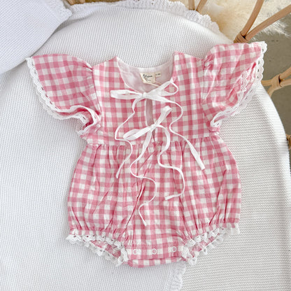 Pink and white checkered baby romper with ruffled details on a white surface.