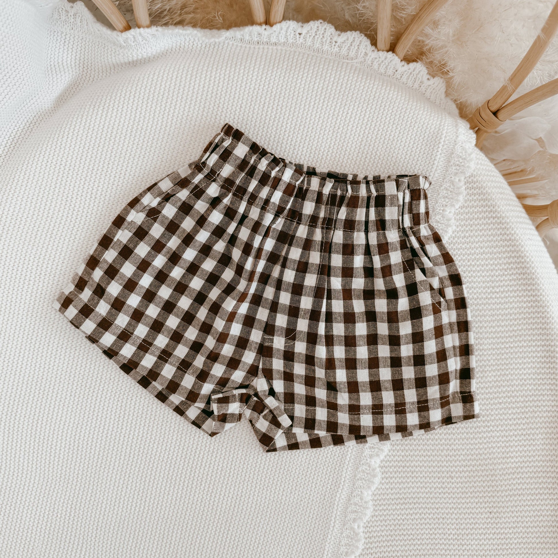 Brown and white checkered shorts on a textured white surface