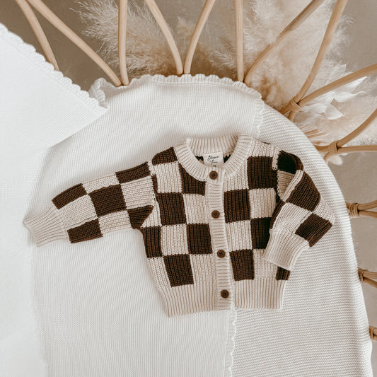 Checkered sweater on a white surface with decorative elements