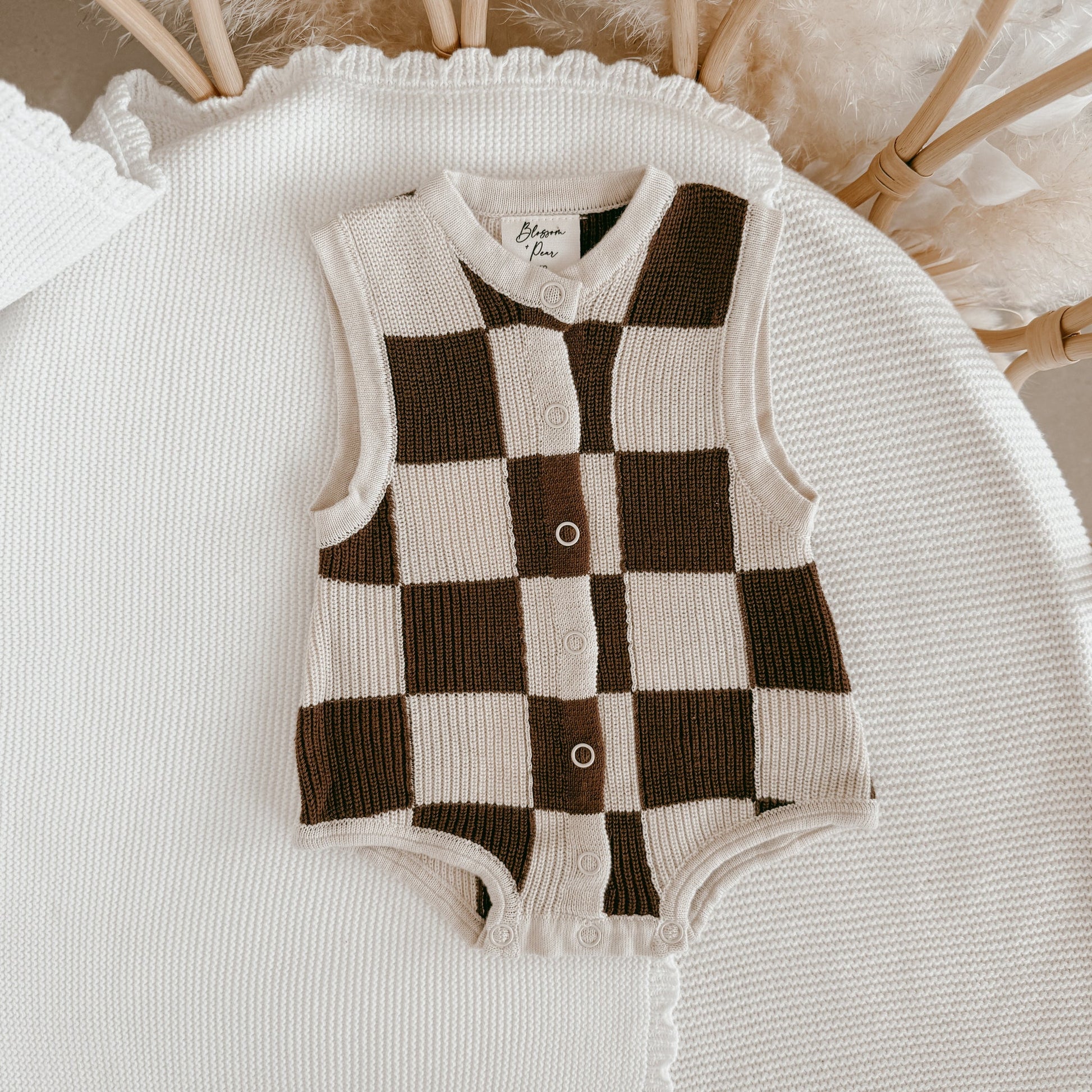 Checkered baby romper on a textured surface with blurred background
