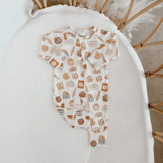 Baby onesie with cookie pattern on a white surface