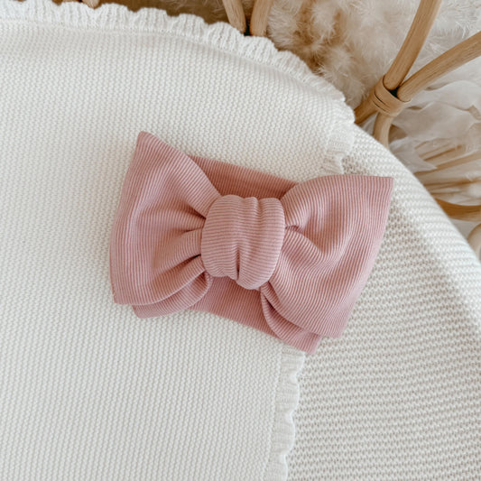Pink bow on a textured white surface with a blurred background