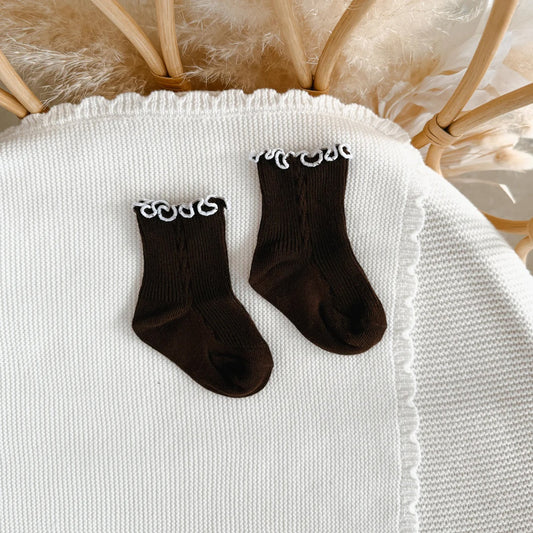 Pair of black socks with white accents on a textured surface