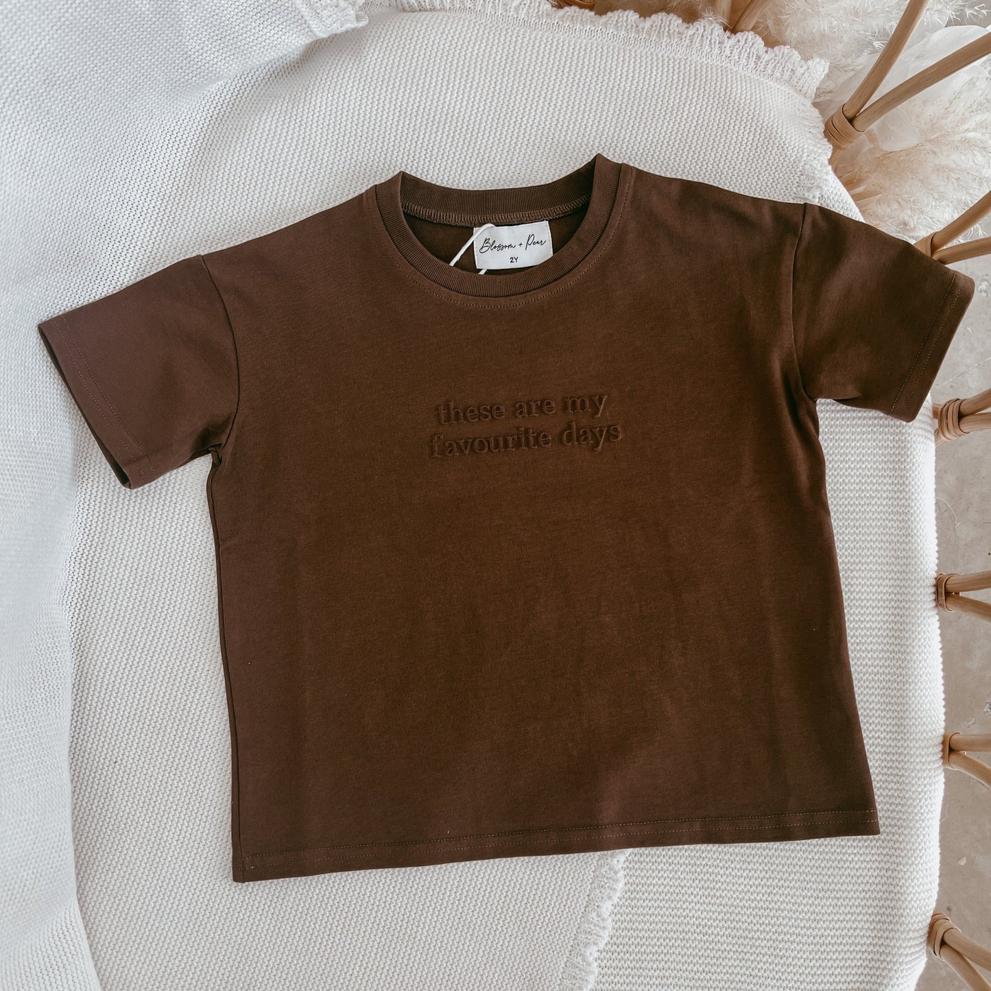 Brown t-shirt with text on a textured surface