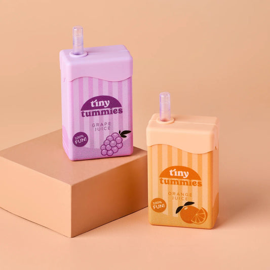 Two 'tiny tummies' juice boxes, one grape and one orange, on a beige background.