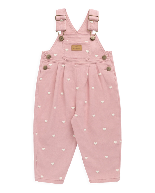Pink children's dungarees with heart patterns on a white background