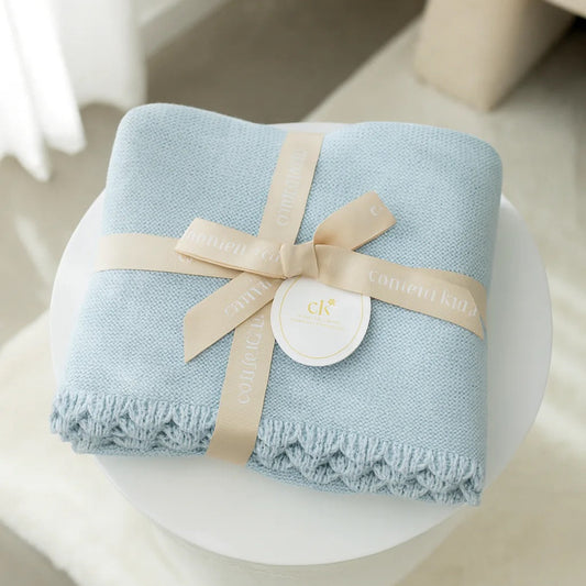 Light blue blanket with a beige ribbon on a white surface