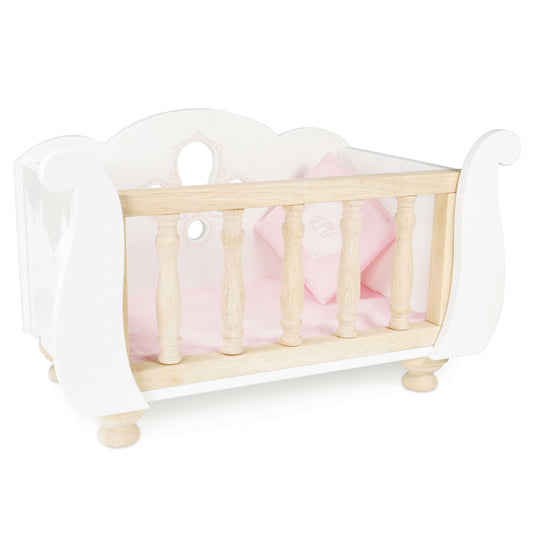 Wooden crib with pink bedding on a white background