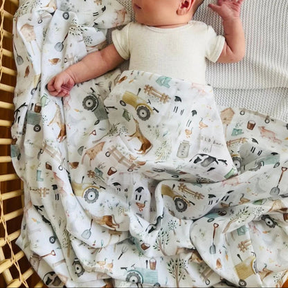 Newborn baby wrapped in a patterned blanket with vehicles, lying on a textured surface.