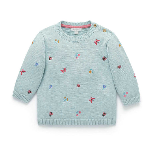 Light blue sweater with floral patterns on a white background