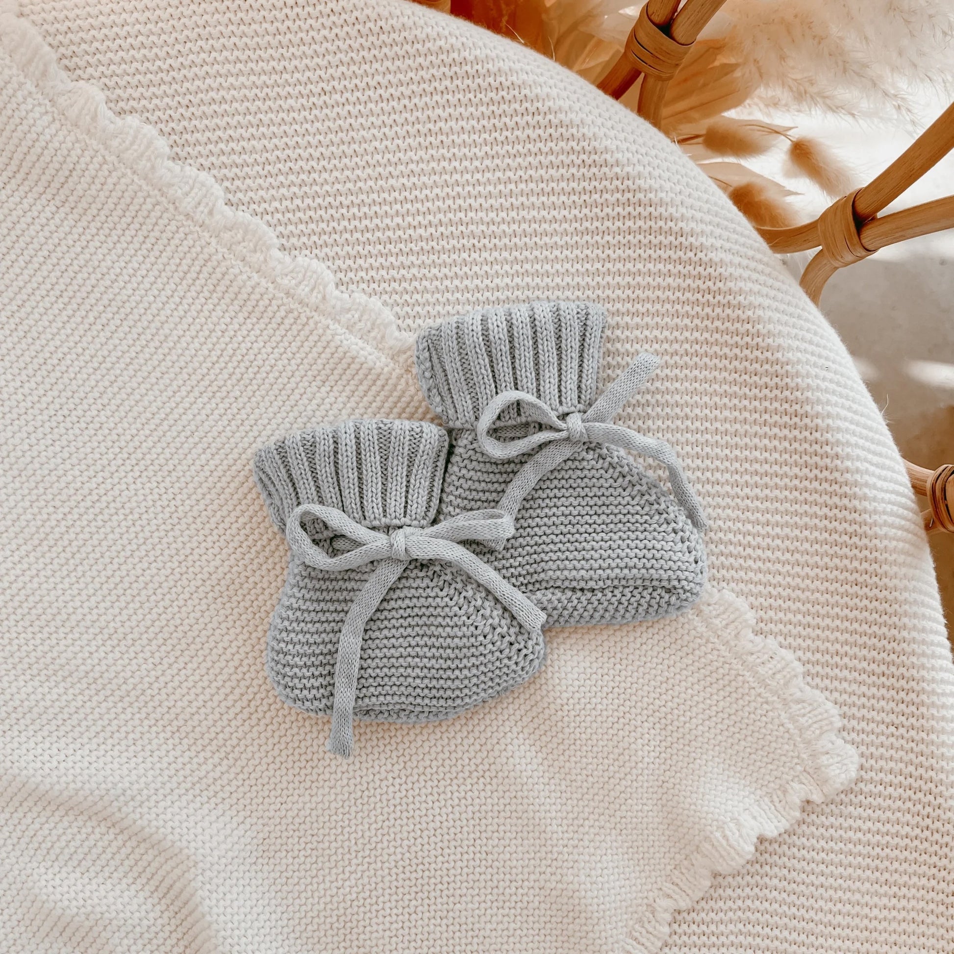 Two gray knitted drawstring bags on a textured surface