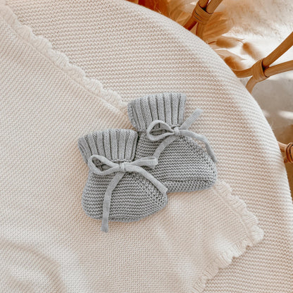 Two gray knitted drawstring bags on a textured surface