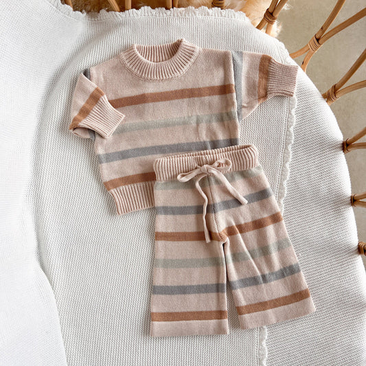 Children's striped sweater and pants set on a textured surface