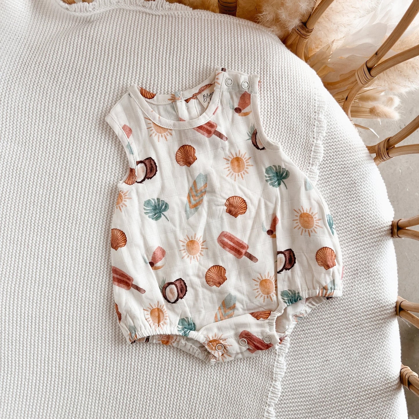 Baby romper with summer-themed print on a textured surface