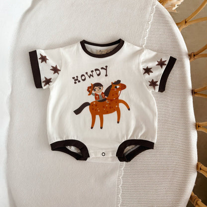 Baby onesie with horse and rider design and 'Howdy' text on a textured surface.
