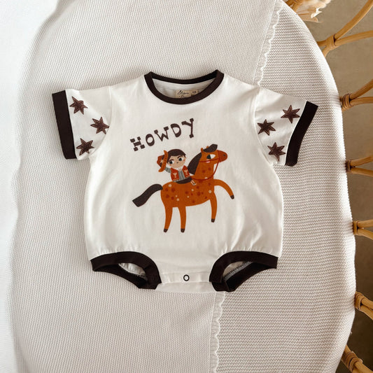 Baby onesie with horse and rider design and 'Howdy' text on a textured surface.