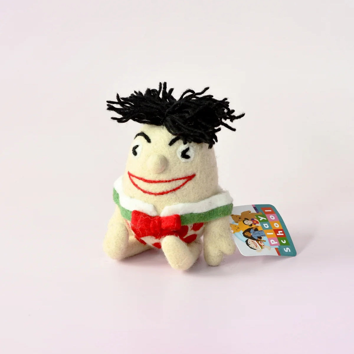 Small plush toy with black hair and a red bow tie on a white background