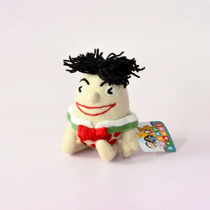 Small plush toy with black hair and a red bow tie on a white background
