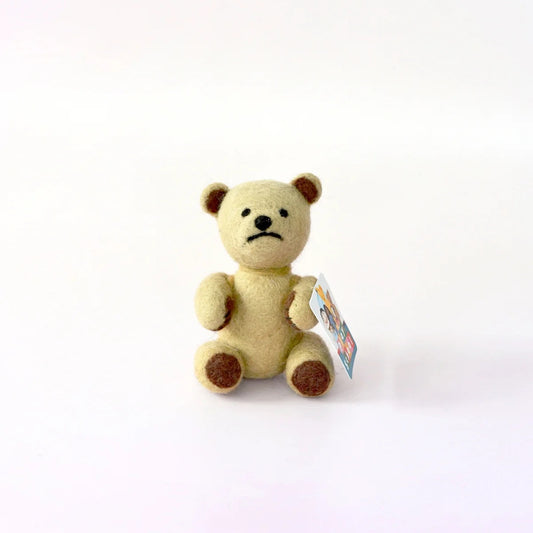 Small beige teddy bear with a tag on a white background