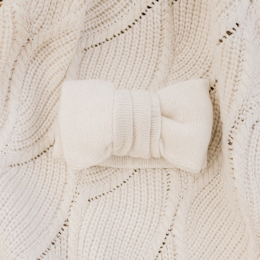 White knitted headband on a textured beige fabric background