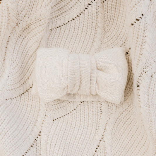 White knitted headband on a textured beige fabric background