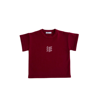 Maroon t-shirt with a small white logo on a white background