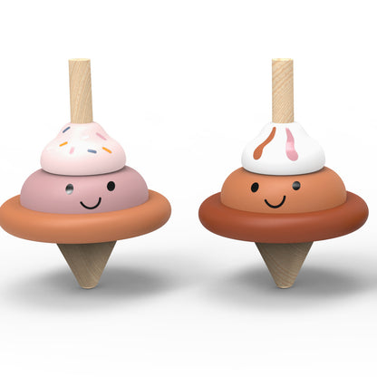 Two wooden toy ice cream cones with smiling faces, shown side by side on a clean white background. One has pink and peach layers with colorful sprinkles, and the other has peach and white layers with pink drizzle.