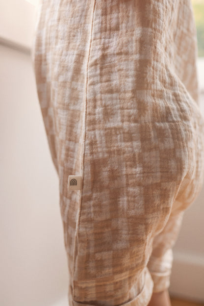 Close-up of a brown and beige patterned garment with a brand logo on a neutral background